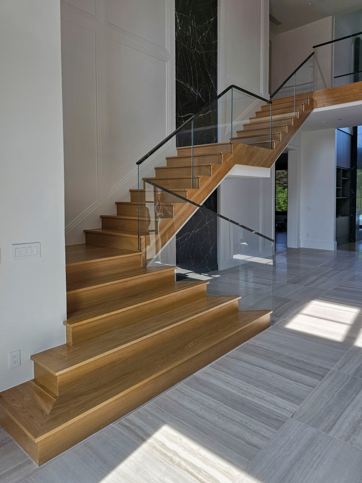 This is an example of an expansive contemporary wood floating staircase in DC Metro with wood risers, mixed railing and decorative wall panelling.