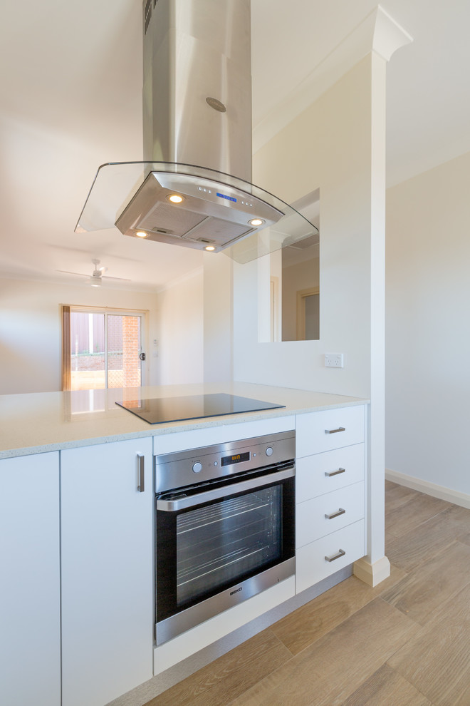 This is an example of a mid-sized contemporary u-shaped eat-in kitchen in Sydney with an undermount sink, louvered cabinets, white cabinets, quartz benchtops, green splashback, glass sheet splashback, stainless steel appliances, ceramic floors and a peninsula.