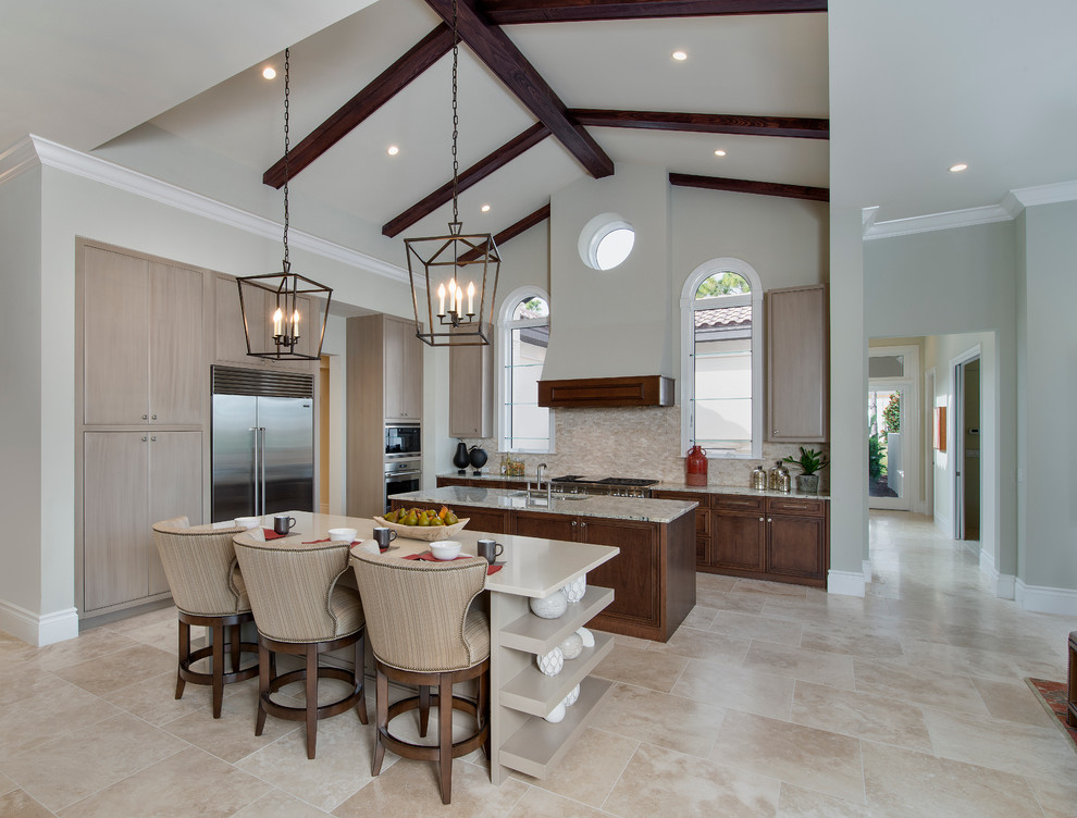 Inspiration for a large transitional l-shaped open plan kitchen in Tampa with a drop-in sink, marble benchtops, beige splashback, stone tile splashback, stainless steel appliances and multiple islands.