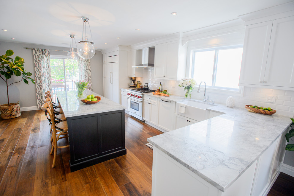 This is an example of a traditional single-wall kitchen in New York with a farmhouse sink, recessed-panel cabinets, white cabinets, white splashback, subway tile splashback, medium hardwood floors and with island.