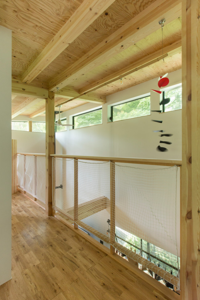 Moderner Flur mit weißer Wandfarbe, braunem Holzboden, freigelegten Dachbalken und Holzdielenwänden in Sonstige