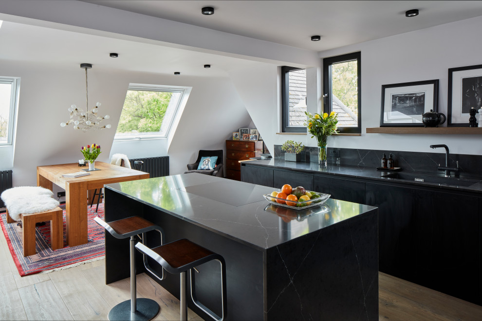 Exempel på ett litet modernt grå grått kök, med en undermonterad diskho, släta luckor, svarta skåp, bänkskiva i kvartsit, grått stänkskydd, rostfria vitvaror, ljust trägolv, en köksö och brunt golv