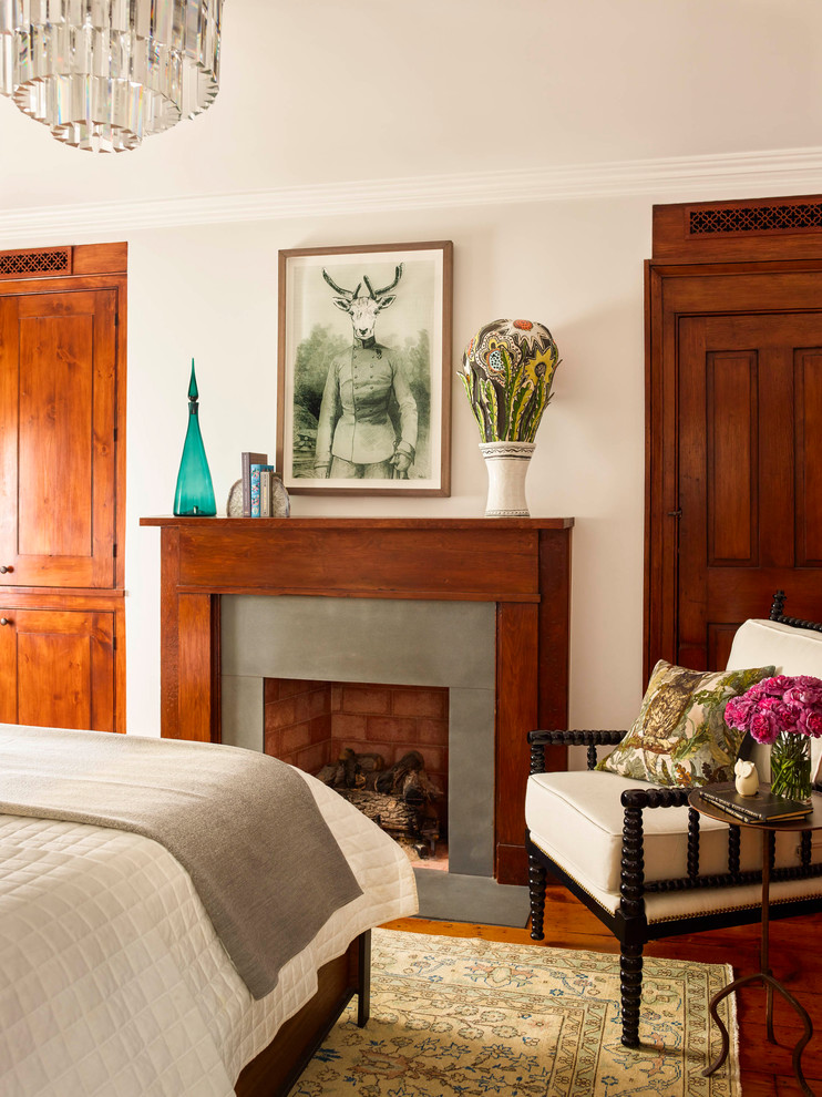 Mid-sized traditional guest bedroom in New York with white walls, medium hardwood floors, a standard fireplace, a wood fireplace surround and brown floor.