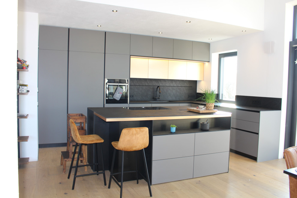 Esempio di una grande cucina design con lavello sottopiano, ante grigie, top in laminato, paraspruzzi nero, pavimento in legno verniciato e top nero