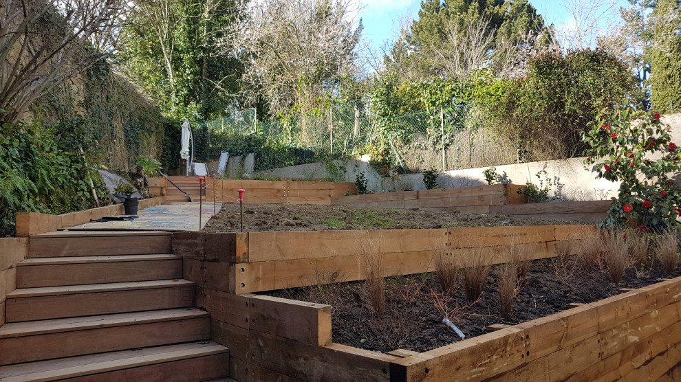 Photo of a mid-sized eclectic sloped partial sun xeriscape for spring in Nantes with a retaining wall and decking.