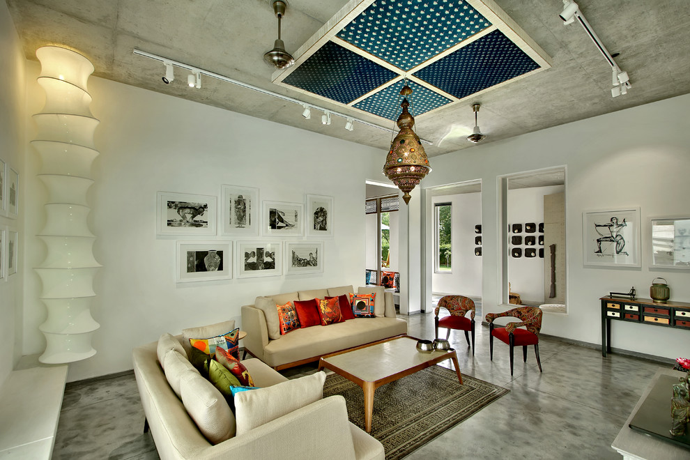 This is an example of an eclectic living room in Ahmedabad with white walls and concrete floors.