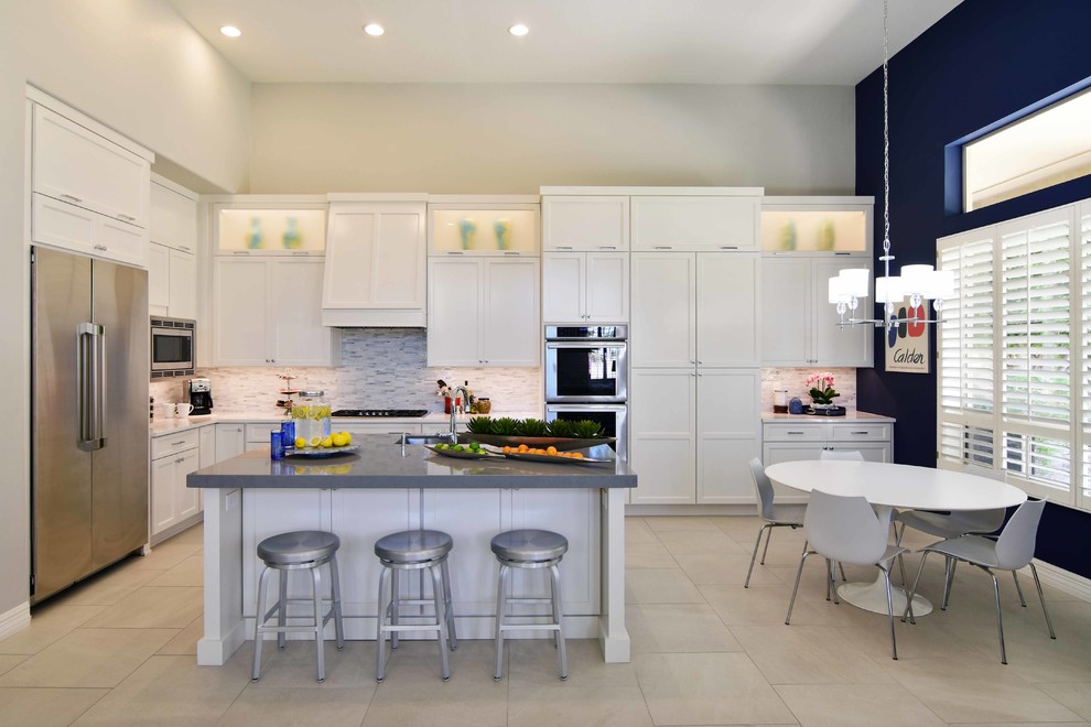 This is an example of a large transitional u-shaped eat-in kitchen in Phoenix with an undermount sink, recessed-panel cabinets, white cabinets, quartz benchtops, white splashback, stone tile splashback, stainless steel appliances, porcelain floors, with island, beige floor and grey benchtop.