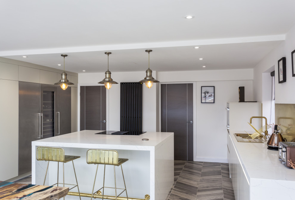Photo of a large contemporary open plan kitchen in Manchester with an integrated sink, flat-panel cabinets, beige cabinets, marble benchtops, metallic splashback, metal splashback, stainless steel appliances, porcelain floors, with island, multi-coloured floor and white benchtop.
