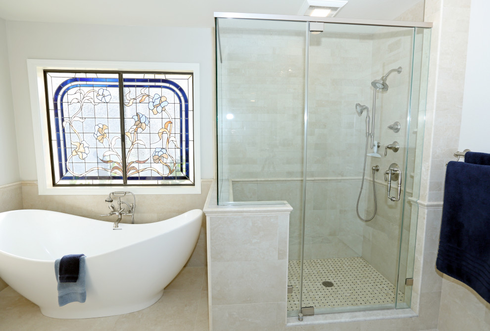 This is an example of an expansive beach style master bathroom in Orange County with recessed-panel cabinets, brown cabinets, a freestanding tub, an alcove shower, a one-piece toilet, beige walls, porcelain floors, a console sink, quartzite benchtops, beige floor, a hinged shower door, white benchtops, a double vanity and a built-in vanity.