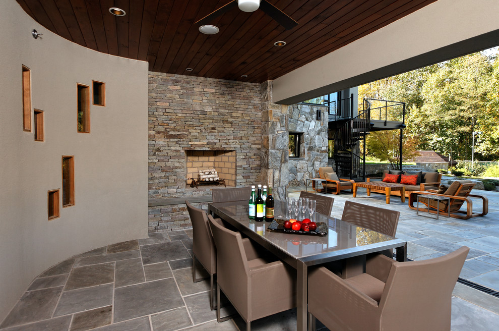 Design ideas for a contemporary backyard patio in DC Metro with a fire feature, natural stone pavers and a roof extension.
