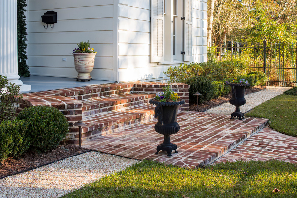 This is an example of a large traditional front yard formal garden in New Orleans with brick pavers.