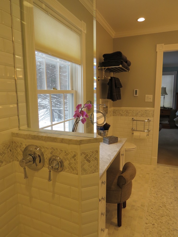This is an example of a mid-sized traditional master bathroom in Portland Maine with an undermount sink, beaded inset cabinets, white cabinets, marble benchtops, an alcove tub, a curbless shower, a wall-mount toilet, multi-coloured tile, mosaic tile, grey walls and marble floors.