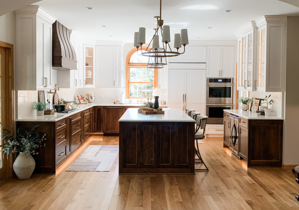 Light wood floor kitchen photo with a double-bowl sink, shaker cabinets, white cabinets, quartz countertops, quartz backsplash, paneled appliances and an island
