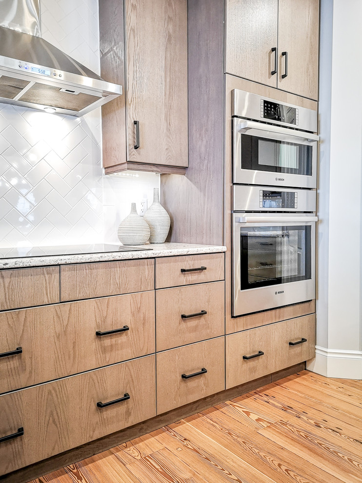 Eat-in kitchen - large transitional u-shaped light wood floor and brown floor eat-in kitchen idea with an undermount sink, flat-panel cabinets, beige cabinets, quartz countertops, white backsplash, subway tile backsplash, stainless steel appliances, an island and white countertops