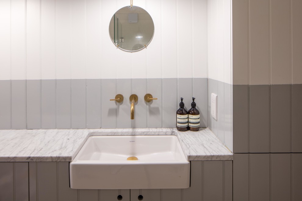 This is an example of a scandinavian kids bathroom in London with shaker cabinets, grey cabinets, grey walls, a trough sink and marble benchtops.