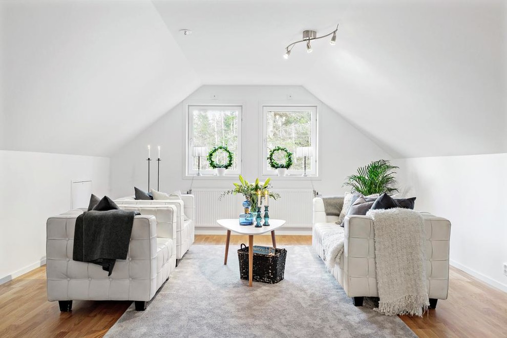 This is an example of a transitional living room in Gothenburg with white walls, medium hardwood floors, no fireplace and beige floor.