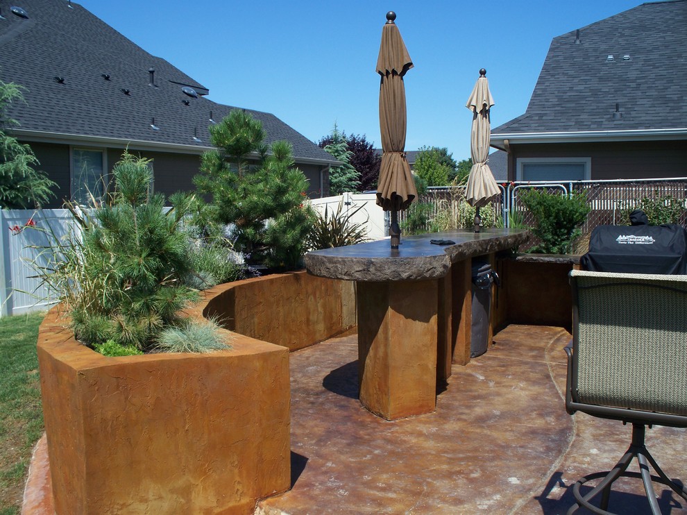 This is an example of a mid-sized country backyard patio in Boise with an outdoor kitchen, concrete slab and no cover.