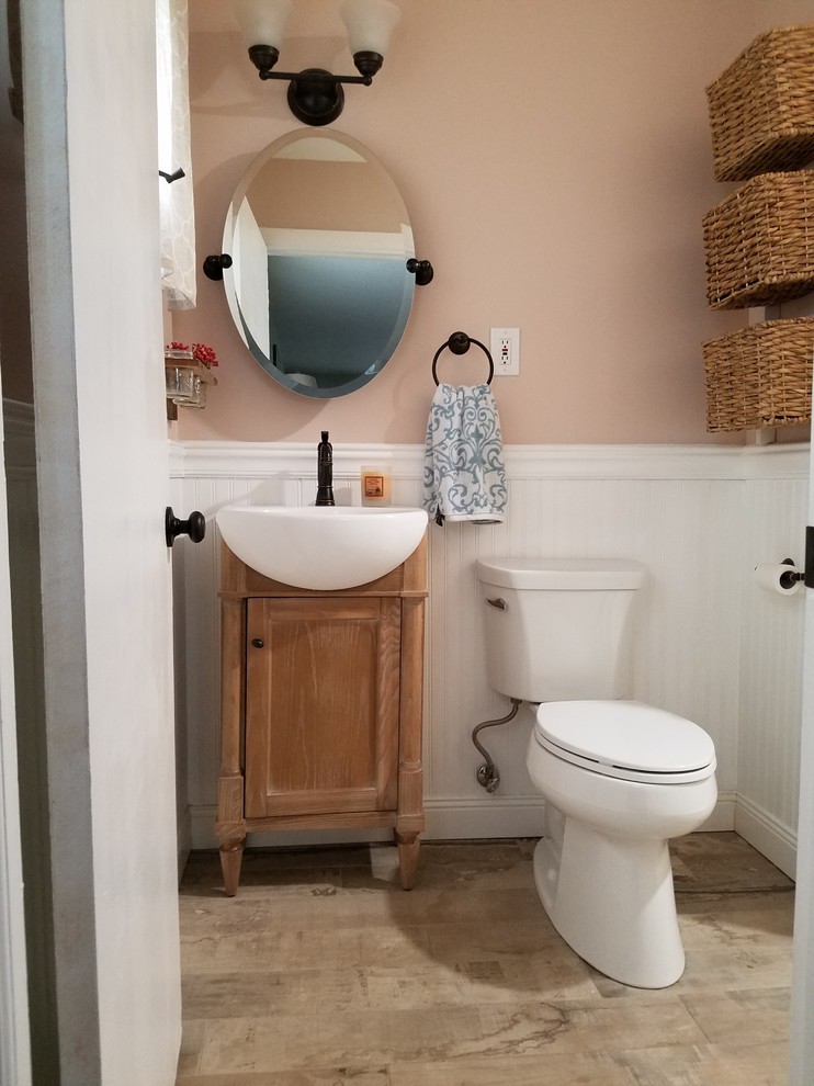 Inspiration for a small country 3/4 bathroom in Bridgeport with shaker cabinets, medium wood cabinets, a two-piece toilet, pink walls, light hardwood floors and a vessel sink.