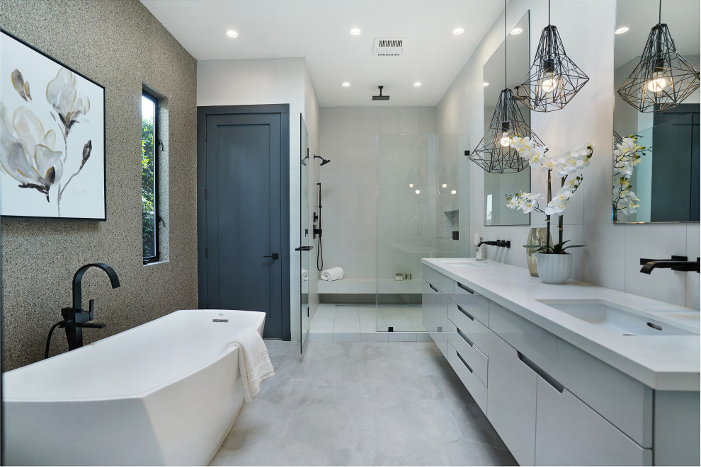 Contemporary bathroom in Los Angeles with flat-panel cabinets, grey cabinets, a freestanding tub, an alcove shower, gray tile, an undermount sink, grey floor, a hinged shower door, white benchtops, a shower seat, an enclosed toilet, a double vanity and a floating vanity.