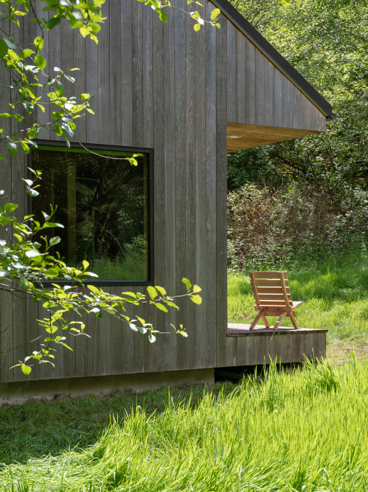 Aménagement d'une petite façade de maison montagne en bois de plain-pied avec un toit à deux pans, un toit en métal et un toit gris.