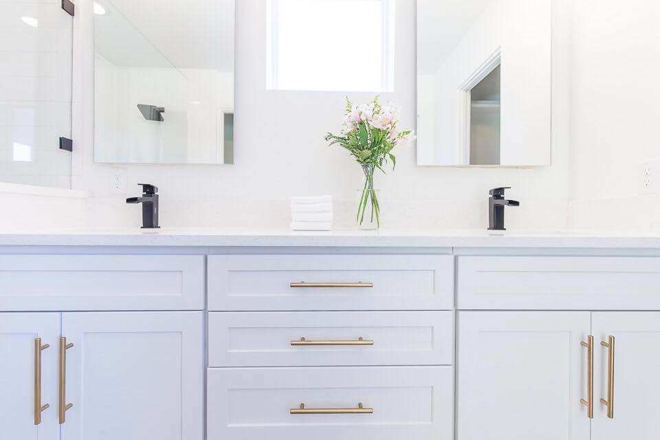 Photo of a mid-sized modern master bathroom in Austin with shaker cabinets, white cabinets, a drop-in tub, a corner shower, a two-piece toilet, white tile, ceramic tile, white walls, brick floors, a drop-in sink and engineered quartz benchtops.