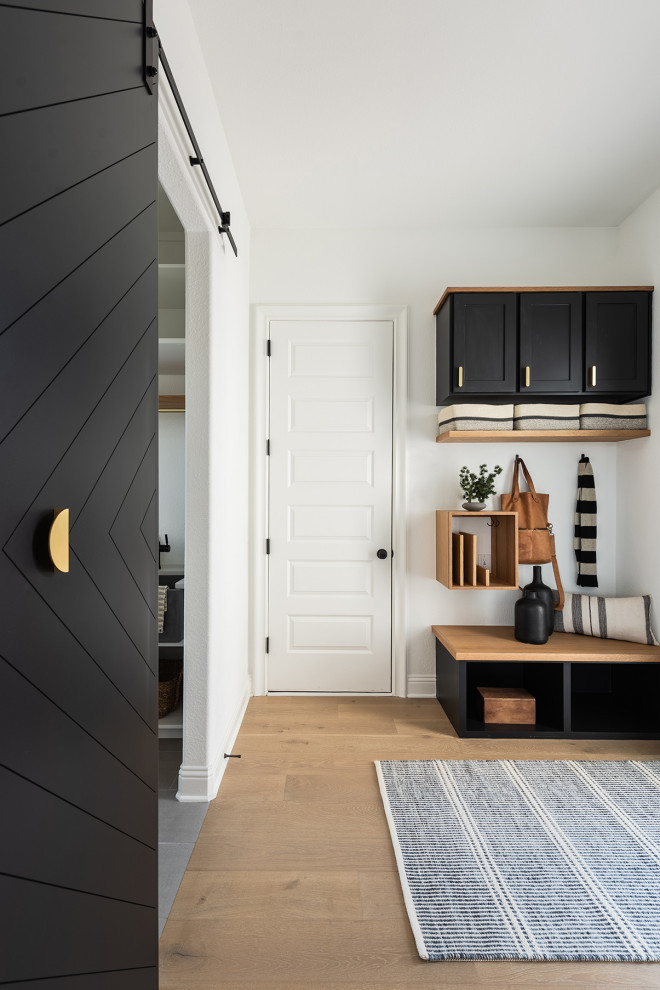 This is an example of a small modern mudroom in Dallas with white walls, light hardwood floors, a black front door and a single front door.