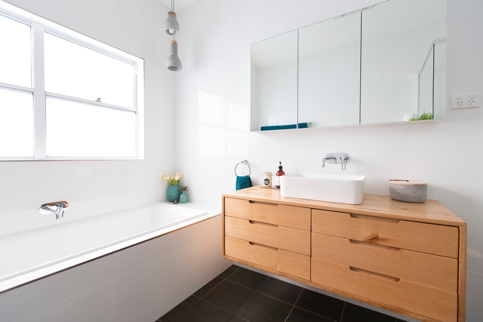 Mid-sized contemporary master bathroom in Newcastle - Maitland with light wood cabinets, a drop-in tub, a corner shower, a one-piece toilet, white tile, white walls, ceramic floors, a drop-in sink, wood benchtops, grey floor and an open shower.