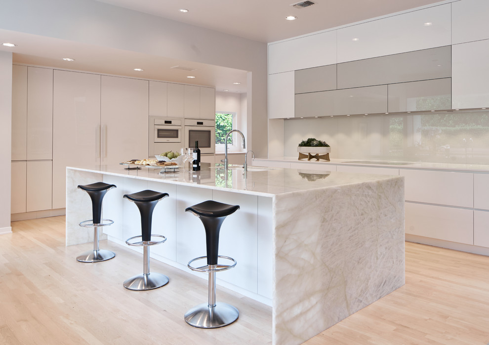 Inspiration for a large contemporary l-shaped eat-in kitchen in Dallas with an undermount sink, flat-panel cabinets, white cabinets, quartz benchtops, white splashback, glass sheet splashback, white appliances, light hardwood floors, with island, yellow floor and white benchtop.