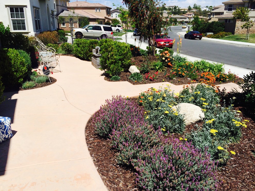 This is an example of a small eclectic front yard full sun garden for summer in Los Angeles with a garden path and concrete pavers.