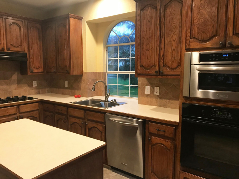 L-shaped kitchen pantry in Dallas with a single-bowl sink, shaker cabinets, white cabinets, quartz benchtops, beige splashback, ceramic splashback, stainless steel appliances, dark hardwood floors, with island, brown floor and white benchtop.