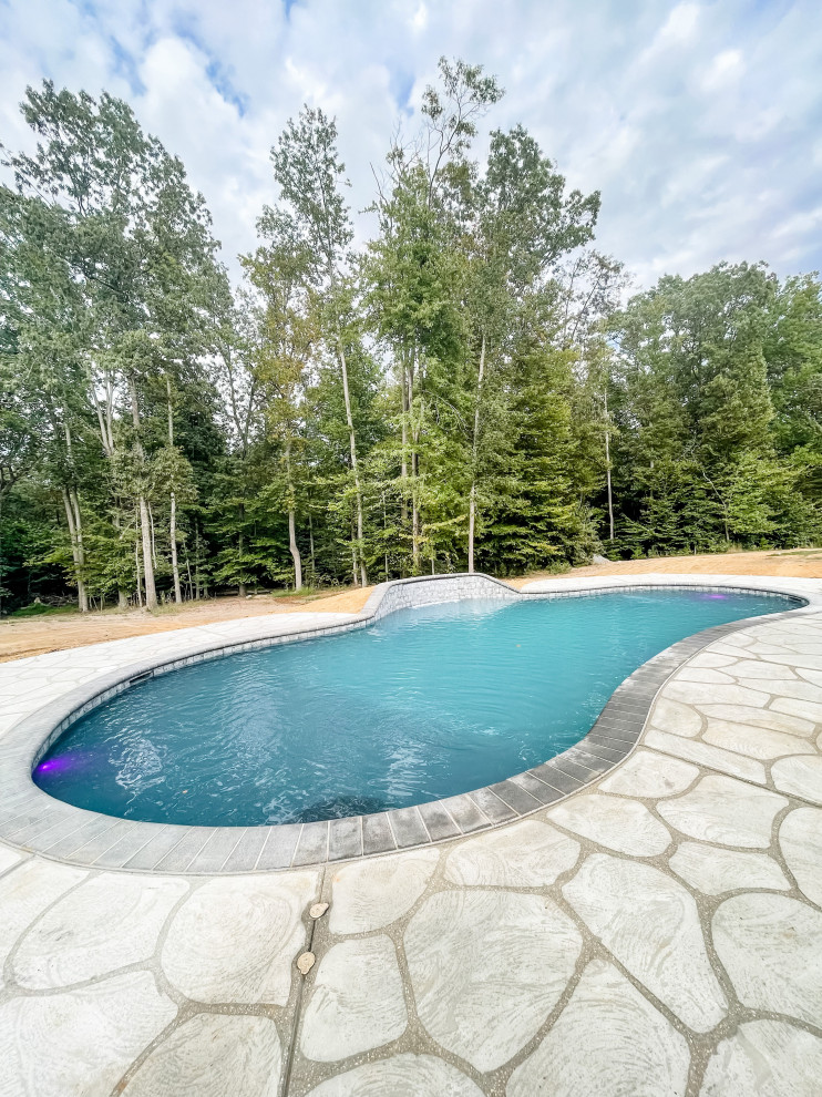 Immagine di una piscina chic personalizzata di medie dimensioni e dietro casa con lastre di cemento