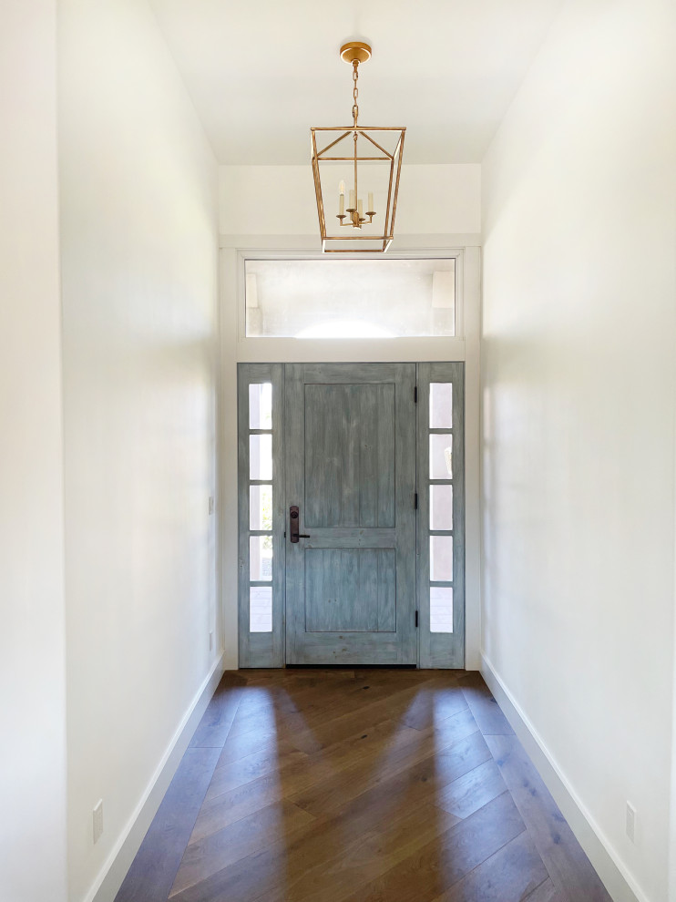 Ispirazione per un ingresso country di medie dimensioni con pareti bianche, pavimento in legno massello medio, una porta singola, una porta blu e pavimento marrone