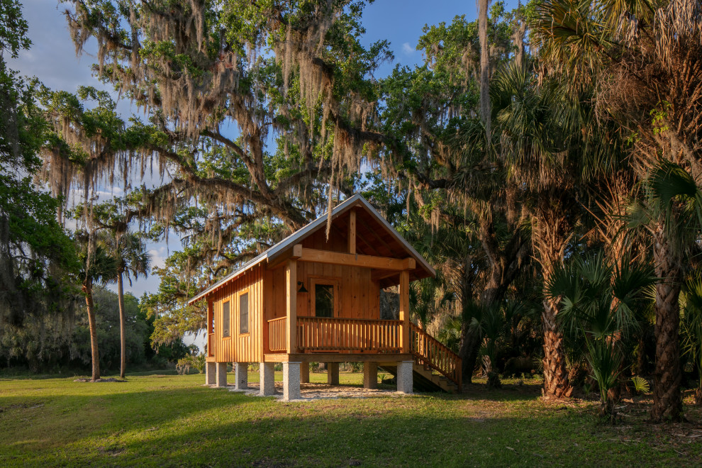 Kleines, Einstöckiges Landhaus Haus mit brauner Fassadenfarbe, Satteldach, Blechdach, grauem Dach und Wandpaneelen in Tampa