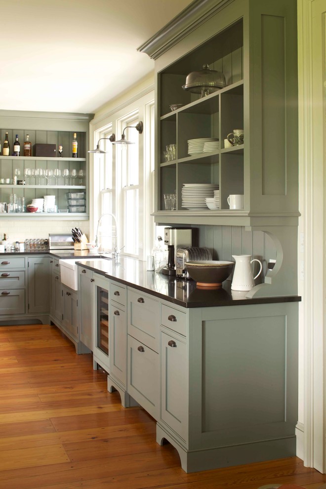 Design ideas for a country l-shaped eat-in kitchen in New York with a farmhouse sink, shaker cabinets, grey cabinets, granite benchtops, white splashback, subway tile splashback, panelled appliances, medium hardwood floors and with island.