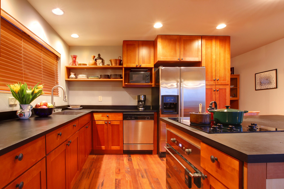 Enclosed kitchen - mid-sized l-shaped medium tone wood floor enclosed kitchen idea with shaker cabinets, medium tone wood cabinets, white backsplash, stainless steel appliances and an island