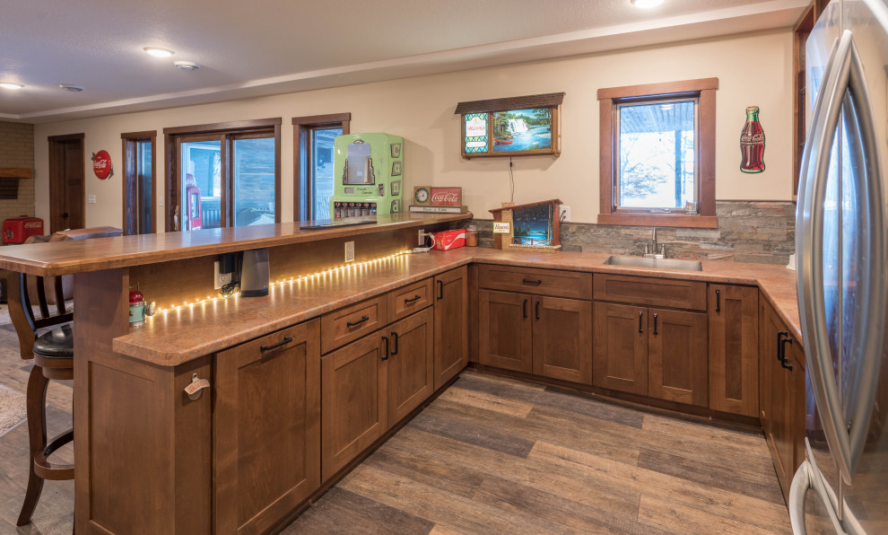 Photo of a small arts and crafts u-shaped home bar in Minneapolis with an undermount sink, shaker cabinets, medium wood cabinets, laminate benchtops, multi-coloured splashback, stone tile splashback, linoleum floors, brown floor and brown benchtop.