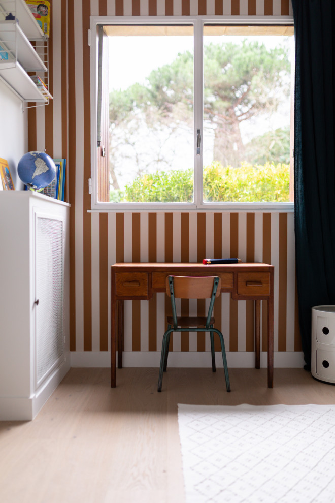Modelo de habitación infantil unisex de 4 a 10 años moderna de tamaño medio con escritorio, paredes amarillas, suelo de madera clara, suelo marrón y papel pintado