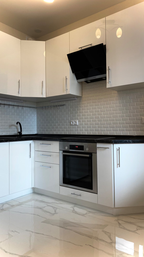 Inspiration for a small contemporary grey and white l-shaped enclosed kitchen in Moscow with a single-bowl sink, flat-panel cabinets, white cabinets, composite countertops, white splashback, ceramic splashback, integrated appliances, porcelain flooring, no island, white floors and black worktops.