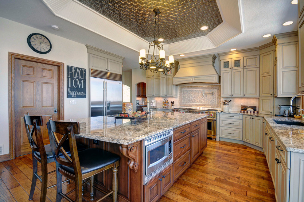 Example of a mid-sized transitional medium tone wood floor eat-in kitchen design in Denver with an undermount sink, furniture-like cabinets, black cabinets, laminate countertops, beige backsplash, subway tile backsplash, stainless steel appliances and beige walls