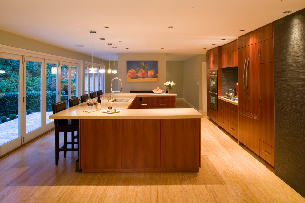 Photo of a contemporary u-shaped open plan kitchen in Vancouver with an undermount sink, flat-panel cabinets, medium wood cabinets, quartz benchtops, grey splashback, stone tile splashback and panelled appliances.