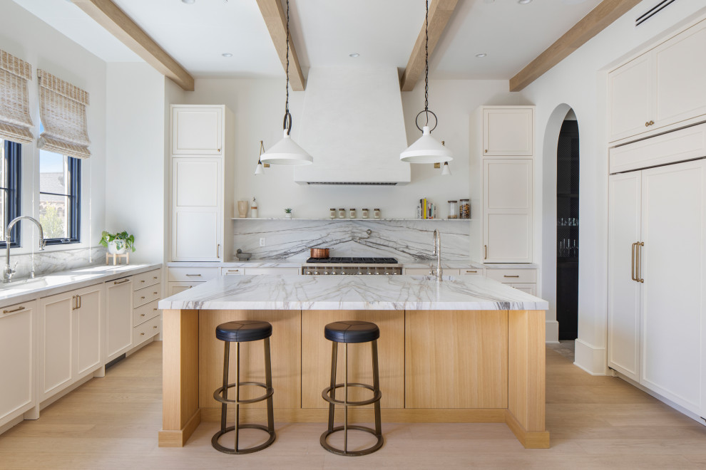 Photo of a transitional u-shaped open plan kitchen in Santa Barbara with an undermount sink, shaker cabinets, white cabinets, marble benchtops, multi-coloured splashback, marble splashback, panelled appliances, light hardwood floors, with island, beige floor, multi-coloured benchtop and exposed beam.