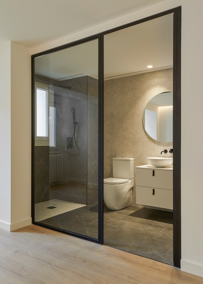 Inspiration for a small modern 3/4 bathroom in Other with white cabinets, a curbless shower, an urinal, beige tile, ceramic tile, beige walls, porcelain floors, a console sink, quartzite benchtops, grey floor, an open shower, white benchtops, an enclosed toilet, a single vanity, a floating vanity and vaulted.