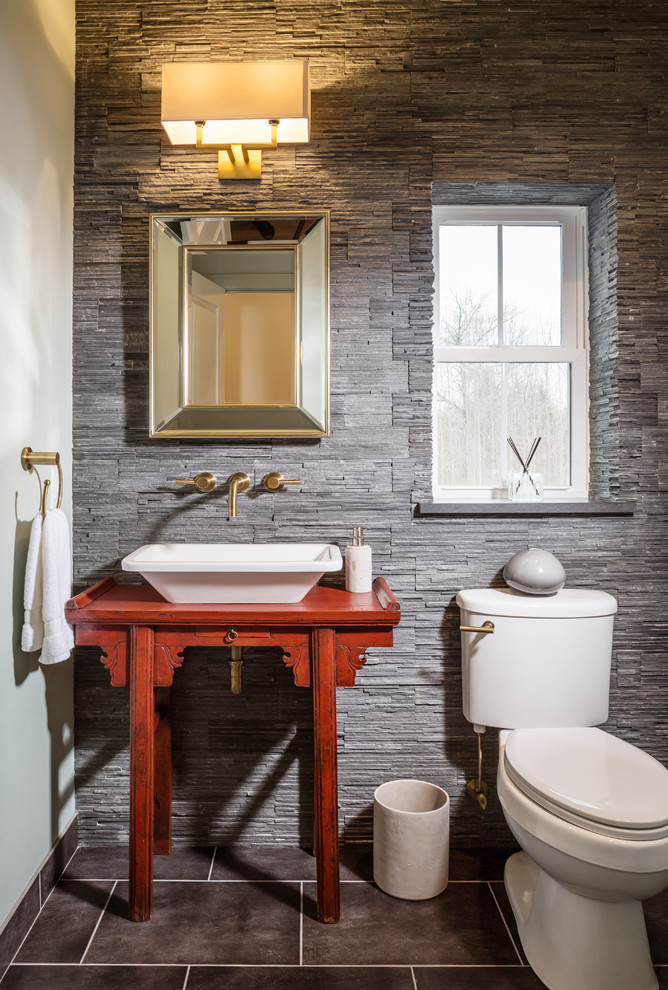 Photo of a small transitional powder room in Milwaukee with a vessel sink, furniture-like cabinets, red cabinets, gray tile, a two-piece toilet, grey walls, ceramic floors, wood benchtops and red benchtops.