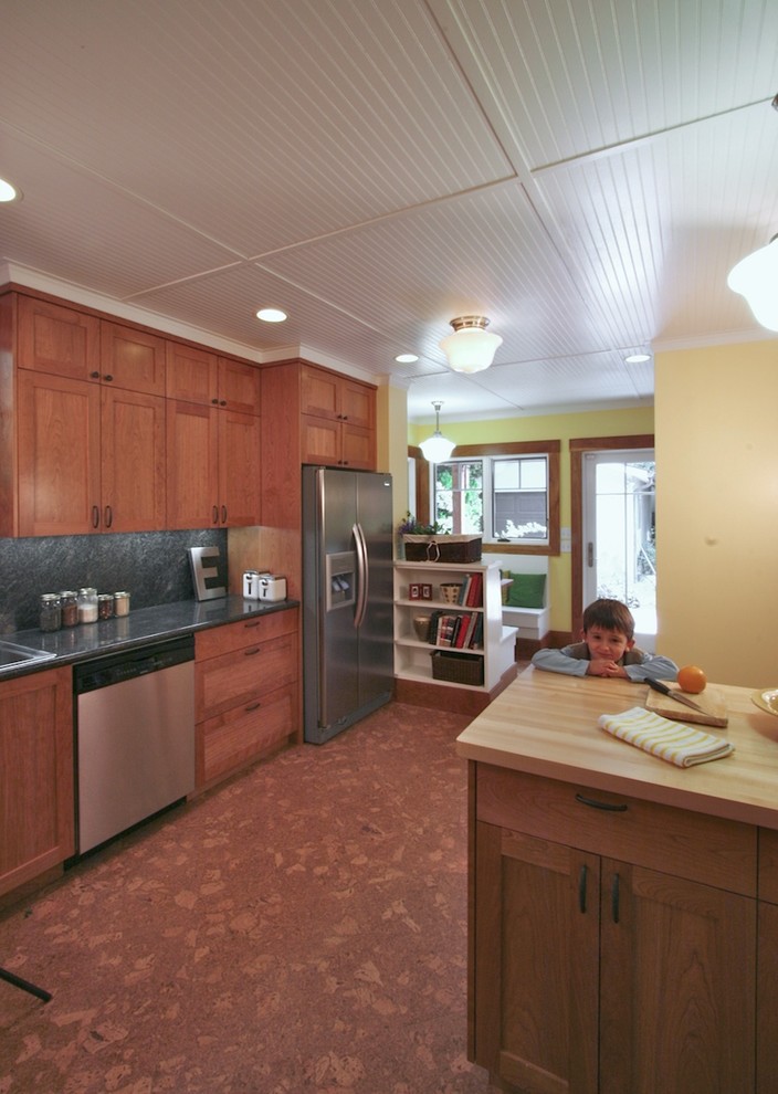 This is an example of a mid-sized arts and crafts l-shaped eat-in kitchen in San Francisco with a double-bowl sink, shaker cabinets, medium wood cabinets, granite benchtops, green splashback, stone slab splashback, cork floors and a peninsula.