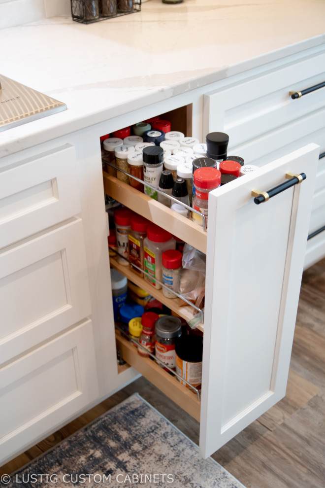 Example of a large transitional l-shaped laminate floor and brown floor open concept kitchen design with an undermount sink, flat-panel cabinets, white cabinets, quartz countertops, white backsplash, ceramic backsplash, stainless steel appliances, an island and white countertops
