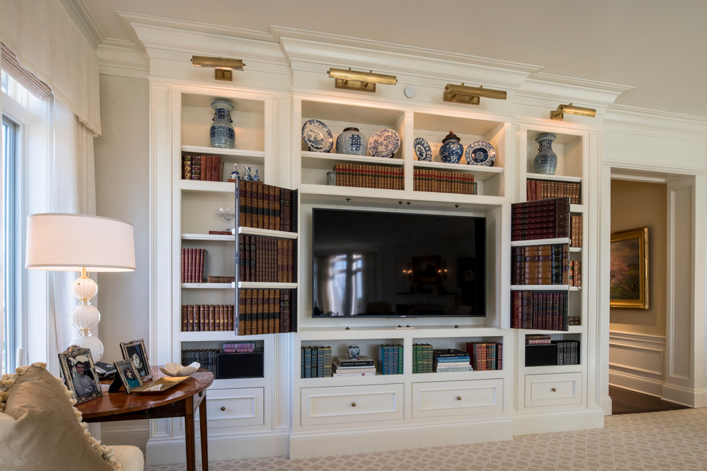 Photo of a mid-sized traditional enclosed family room in Cincinnati with a library, beige walls, carpet, no fireplace, a concealed tv and beige floor.