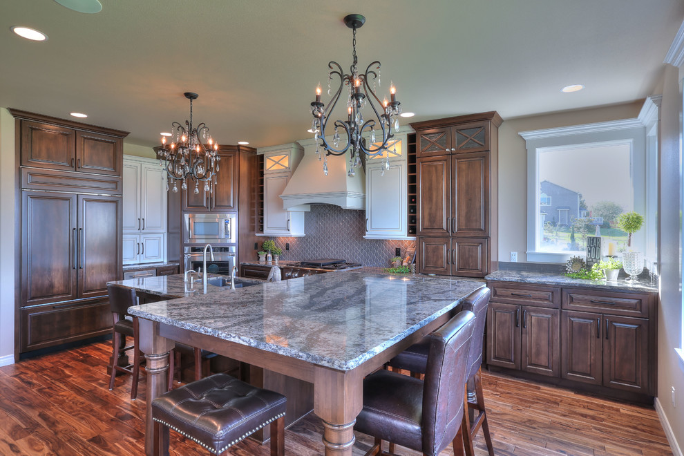 Inspiration for a large transitional l-shaped medium tone wood floor eat-in kitchen remodel in Seattle with an undermount sink, medium tone wood cabinets, granite countertops, brown backsplash, stainless steel appliances and an island