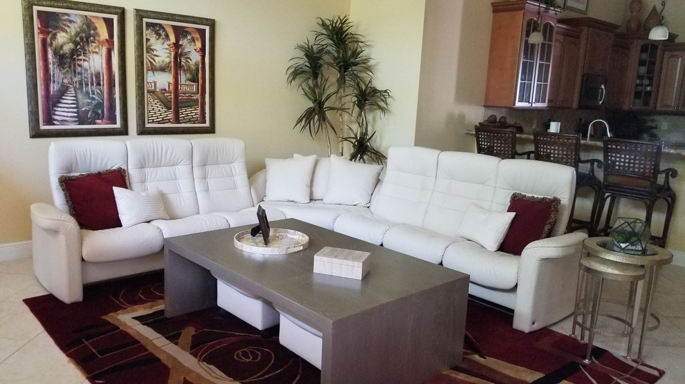This is an example of a mid-sized transitional open concept family room in Miami with beige walls, ceramic floors, a wall-mounted tv and beige floor.