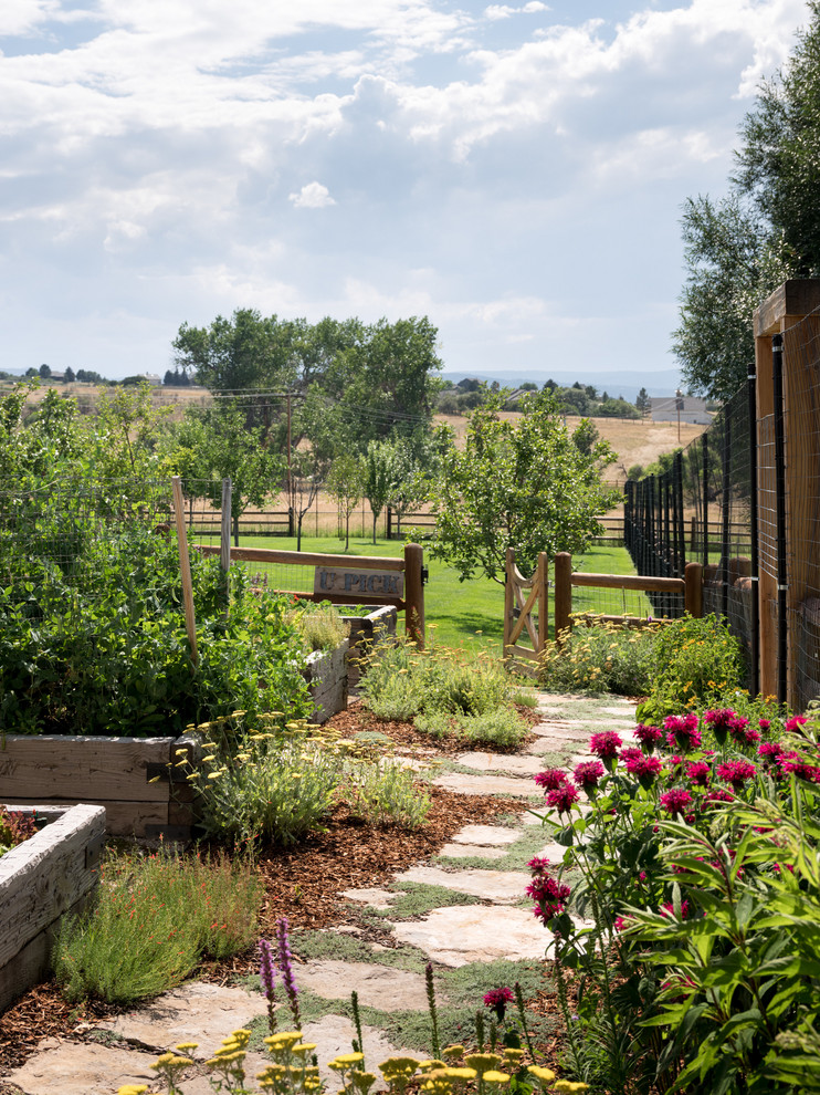 This is an example of a country backyard full sun garden for summer in Denver with a vegetable garden and natural stone pavers.