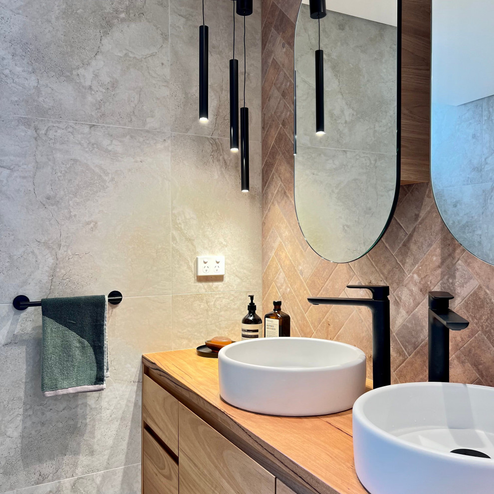 Photo of a small mediterranean bathroom in Sydney with flat-panel cabinets, brown cabinets, a freestanding tub, a curbless shower, a wall-mount toilet, beige tile, ceramic tile, beige walls, ceramic floors, a drop-in sink, wood benchtops, beige floor, a hinged shower door, brown benchtops, a double vanity and a floating vanity.